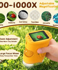 Kids Microscope 200 to 1000X With 2 Inch IPS Screen STEM Science Kit for Ages 3 12 Educational Dope Toy for Exploring Leaves Coins Insects and More Kid Friendly Bright Yellow handheld microscope in grass with screen and zoom controls