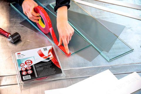 Person using VHB 4910F Clear Double Sided Acrylic Foam Tape for Transparent Bonding, 19 mm x 11 m, on glass, adhesive roll