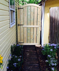 Wooden garden gate installed with 6 Pack 8 Inch T Strap Hinges Heavy Duty Shed Door Hinges Gate Strap Black Tee Hinge, surrounded by flowers.