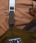 Detailed view of Dan's rugged wear hunting gear showing the brown fabric and metal strap system for adjustable fit.