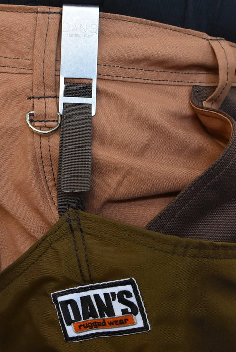 Detailed view of Dan's rugged wear hunting gear showing the brown fabric and metal strap system for adjustable fit.
