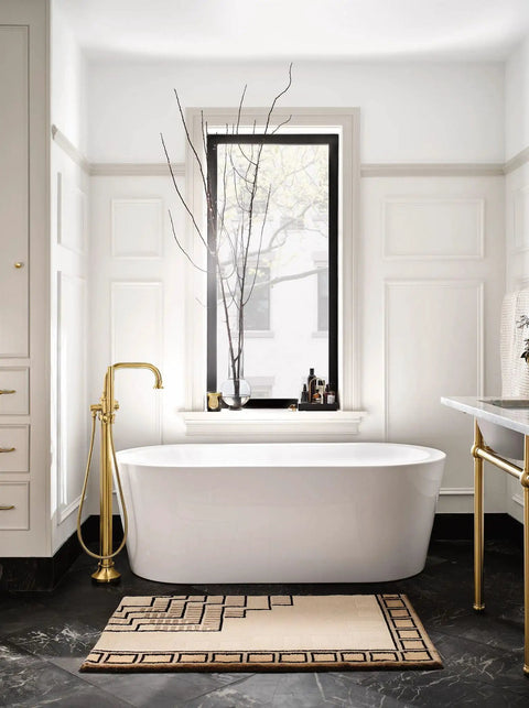 Elegant bathroom with freestanding tub, gold fixtures, window view, and luxurious decor, showcasing modern design.