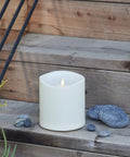 Outdoor Moving Flame Pillar Candle With Remote Included, IPX4 weatherproof LED, ivory 6 by 6 inches on wooden steps with pebbles
