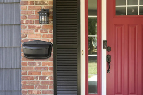 Black Wall Mount Mailbox Crafted From Die Cast Aluminum With Powder Coat mounted on brick next to a red door.