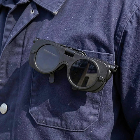 Heavy Duty Black Welding Safety Glasses With Dual Layer Lens To Block Bright Arc Light, resting on a work shirt pocket.