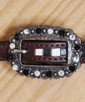 Top Shelf Western Leather Horse Tack Set Bringing The Boss Vibe To Every Ride With A Custom Headstall And Breast Collar Hand Carved With Vibrant Floral Patterns And Durable Antique Copper Hardware. Decorative buckle with silver and black accents on brown leather strap.