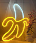 Banana Neon Sign LED Light 11.4 x 7.9 Inches USB or Battery Powered wall decor night lamp illuminating beside dried flowers.