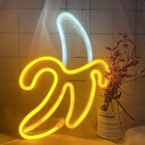 Banana Neon Sign LED Light 11.4 x 7.9 Inches USB or Battery Powered wall decor night lamp illuminating beside dried flowers.