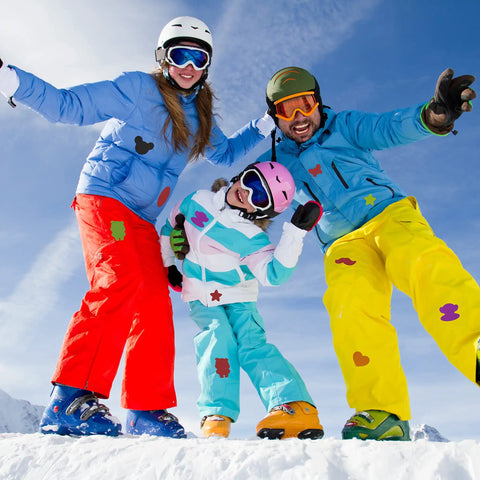 Group skiing wearing colorful snow gear with visible patches, demonstrating Two Pack Nylon Stick On Repair Patches For Outdoor Gear Waterproof Patch Kit 10x20cm For Down Jackets Tents Sleeping Bags And Other Fabrics Great For Camping Hiking And Travel Gear