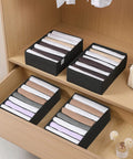 4 Pack T Shirt Drawer Organizers With Eight Grid Compartments For Closet Storage Keeps It Tidy Built From Durable Nonwoven Fabric With Sturdy PP Board Sides Washable Organizer For Folded Clothes Leggings Silk Scarves Black neatly placed in a wooden drawer showcasing various compartments filled with folded clothes.