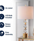 Clear And Brass Gold Crystal Table Lamp With Faceted Orb Design displayed on table, white drum shade, modern glam style.
