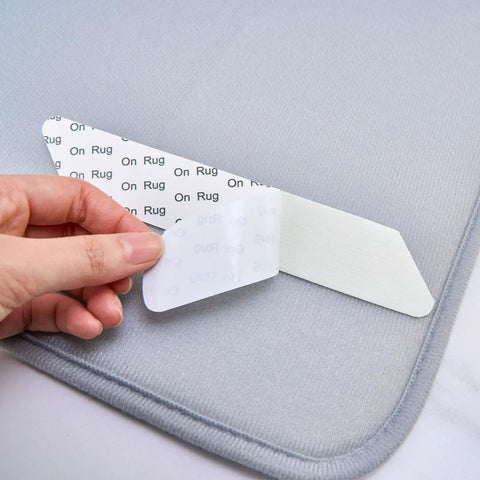 Close-up of a hand peeling a sticky corner of an 8 Pack Washable Non Slip Rug Pads Double Sided For Floors Black Reusable Rug Grips