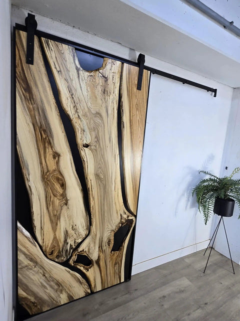 Handcrafted Live Edge Spalted Hackberry Barn Door With Custom Sizing Made To Order In Minnesota Totally One Of A Kind Rustic Modern Wood Door For Hallway Or Entryway, shown from the side angle in an interior setting.