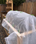 Six Pack Of 7 Foot Fiberglass Greenhouse Hoops For Raised Beds with netting cover, setup in garden setting.