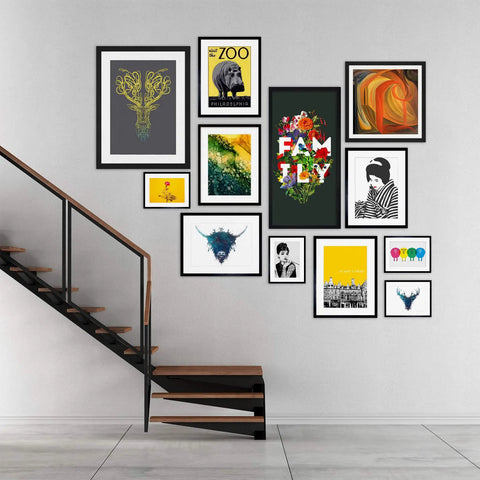Gallery wall with various framed prints above a modern wooden staircase in a minimalist interior