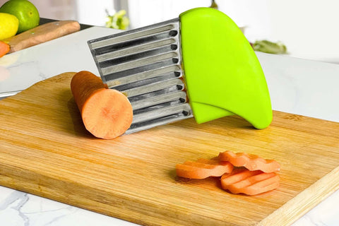 KLEENE stainless steel crinkle cutter with green handle on cutting board; carrot slices nearby