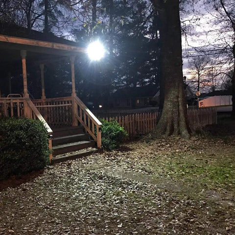 Two Pack Solar Street Lights Outdoor With Motion Sensor 10000LM illuminating a porch and yard at dusk with bright LED light