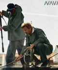 Two men wearing Pro-Grade 0.70mm PVC Fishing Rain Suit Jacket And Bib Pants Set For Commercial Anglers Brigg 44 in dark green, working on a fishing boat