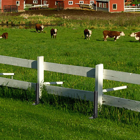 Built Different Heavy Duty Steel Fence Post Anchors And Ground Spikes Repair Kit No Sweat Setup Fixes Leaning Wood Posts With Rust Resistant Black Powder Coating For Durable Yard Care 8 Pack near wooden fence in green field with cows.