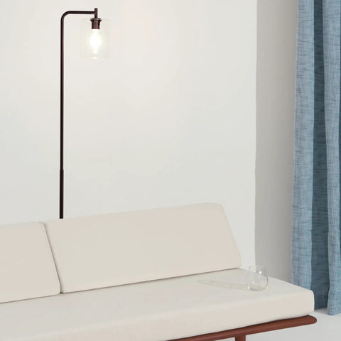 Tall Edison Bulb Floor Lamp With Glass Shade In Bronze Finish beside a white sofa, adding industrial vintage style to room.