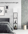 Black space saving floor lamp with shelves next to a bed in a modern room, showcasing stylish decor items.