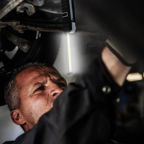 Mechanic using Ultra Bright Handheld LED Work Light With 250 And 500 Lumens 6500K Daylight Magnetic Base Foldable And Rechargeable Flood Light Hanging Hook Emergency Flashing Mode Compact Portable Work Lamp in a dark garage setup.