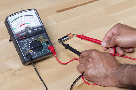 Hands using GMT 319 Multimeter Tester For Electric Pros And DIYers, RJ45 And RJ11 Ports with analog display on table
