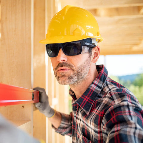 Heavy Duty Boss Level Safety Bifocal Glasses With Rugged Side Shields Kickass Impact Resistant ANSI Certified Eye Gear Smoke Lens Tough Black Frame Multipack For Worksite Grind worn by a worker leveling wood.