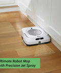 Smart Mapping Robotic Mop With WiFi Connectivity And Jet Spray For Multi Room Cleaning That Recharges And Resumes, Works With Alexa, White mop cleaning hardwood floor next to cabinets.