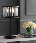 Oil Rubbed Bronze Two Light Metal And Crystal Table Lamp With Traditional Geometric Bedside Design For Living Room Or Bedroom, Linear Crystals, LED Bulbs Included, 21.5 Inch Tall on a table beside flowers and books