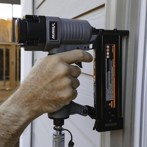 Hand gripping the Straight Shooter Pneumatic Brad Nailer 18 Gauge for installing trim on a wall, showcasing its steel construction.
