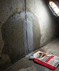 Two Pack 2.2 Pound Grey Concrete Crack Filler Self Leveling Sealant applied on wall with product tube in view