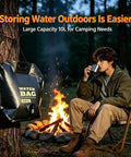 Heavy Duty Portable Camping Water Bag With Spigot for Outdoor Drinking near campfire, 10L black, hanging on tree.