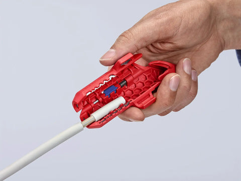 Hand using Workhorse Ergostrip Cable Stripping Tool with ergonomic pistol grip on white round damp-proof cable.