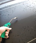 Person using Deluxe Four Inch Air Blow Gun With Removable One Half Inch Tip Green Finish on wet surface for cleaning.