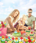 Family playing on sand with Flower Garden Building Toy With Insect Pegs 153 Piece STEM Stacking Pretend Play Set.