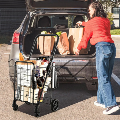 Foldable Grocery Hauling Cart With Dual Basket And 360 Degree Wheels filled with groceries, parked beside a car trunk.