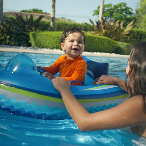 Child in orange shirt on Remote Control Baby Pool Float With Enclosed Propeller Guard, Motorized Toddler Boat For Ages 1 To 4
