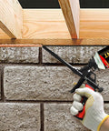 Heavy Duty Foam Gun For Caulking And Sealing used for applying foam between brick and wood structure, precise trigger control visible.