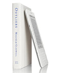 Sleek White Second Gen Ereader Features A Sharp Six Inch Screen And Free 3G Wireless To Pull Down Books Anywhere, placed beside a white book.