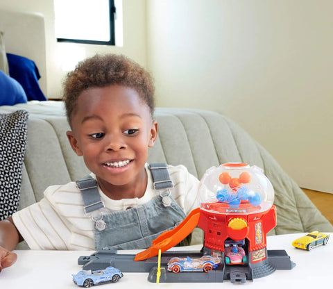 Child playing with Hot Wheels Downtown Candy Shop Playset With 1:64 Scale Die-Cast Donut Shaped Car and gumball machine.