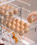 Clear BPA Free Refrigerator Organizer Bins With 18 Egg Tray Stackable Holder for fridge storage, hand reaching for egg
