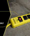 Beefy Metal Surge Protector Strip With Six Outlets And 15 Foot Yellow Cord, shown with connected plugs on workshop floor.