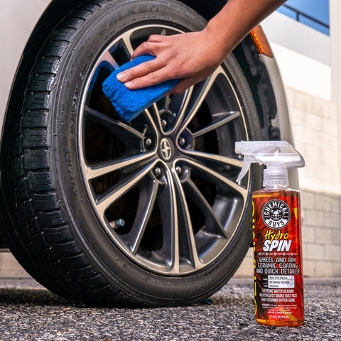 HydroSpin Wheel And Rim Ceramic Coating And Quick Detailer Spray 16 Oz used on a car tire with a blue sponge in hand