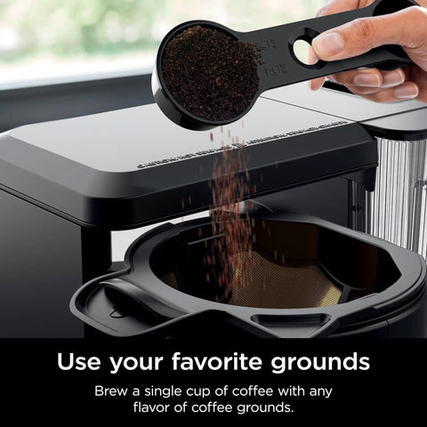 Hot And Iced XL Coffee Maker With Rapid Cold Brew Four Brew Styles Eight Cup Sizes From Small Cup To Travel Mug Barista Grade Single Serve Brewer 12 Cup Carafe Permanent Filter Removable Reservoir Black CM371, showing coffee grounds being added to filter.