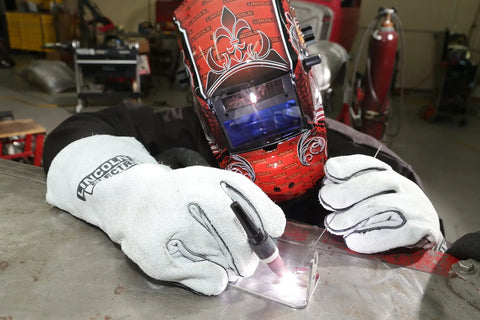 A welder wearing a helmet and Leather Welding Gloves KH641 Pro Grade Heat Resistant Gauntlet Cuff working on a metal surface.