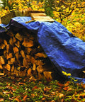 Blue 10 X 20 Ft Waterproof Tarp Cover With 4 Mil Thick Poly Material covering firewood in forest, rope sewn edges visible.
