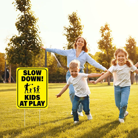 3 Pack Slow Down Kids At Play Signs 14.2 By 11 Inches Double Sided Weatherproof Yard Street Safety Sign Yellow High Visibility For Neighborhoods And Outdoor Use shown in a park setting with children playing