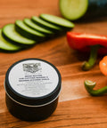Wood Butter 4 Fl Oz Cutting Board Wax Conditioner For Butcher Block And Wooden Kitchen Tools All Natural Food Grade Mineral Oil And Beeswax jar on wooden surface next to vegetables.