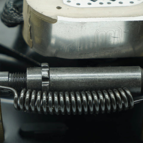 Close-up of a trailer brake magnet actuator with a coiled spring and a Dexter-branded brake rotor.
